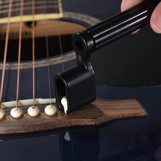 A Black Guitar String Winder shown being used on an acoustic guitar.