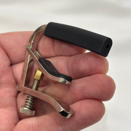 Alice acoustic / electric guitar capo in a hand against a white background.