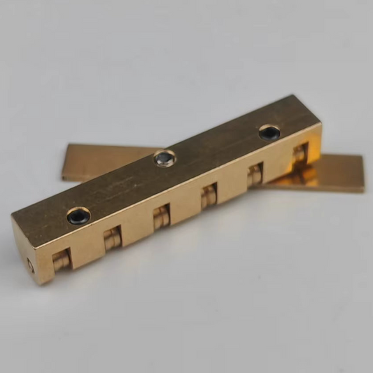 The underside of a brass electric guitar roller nut on a white background.