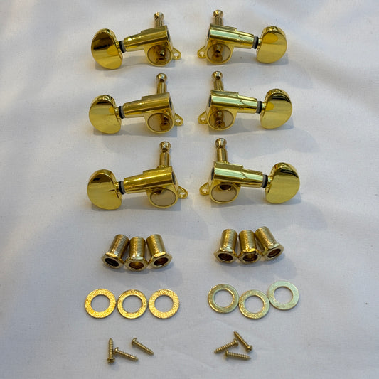 Set of gold guitar tuners with kidney shaped buttons and related parts on a white background