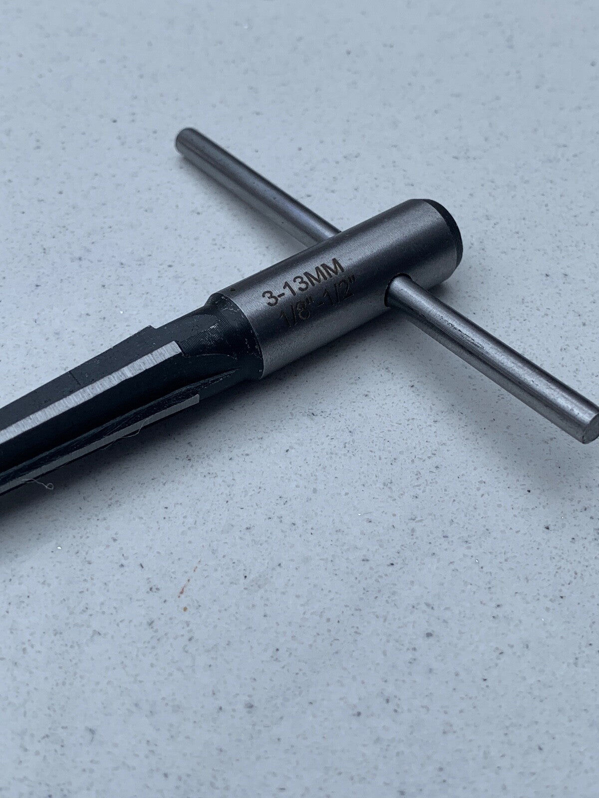 Close up of a Guitar Hole Reamer from the side against a grey background.