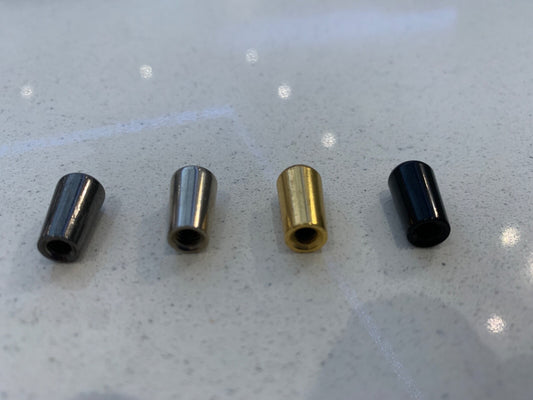 The underside of Four electric guitar Guitar Toggle Switch Tips, LP-style, in different finishes on a grey background.