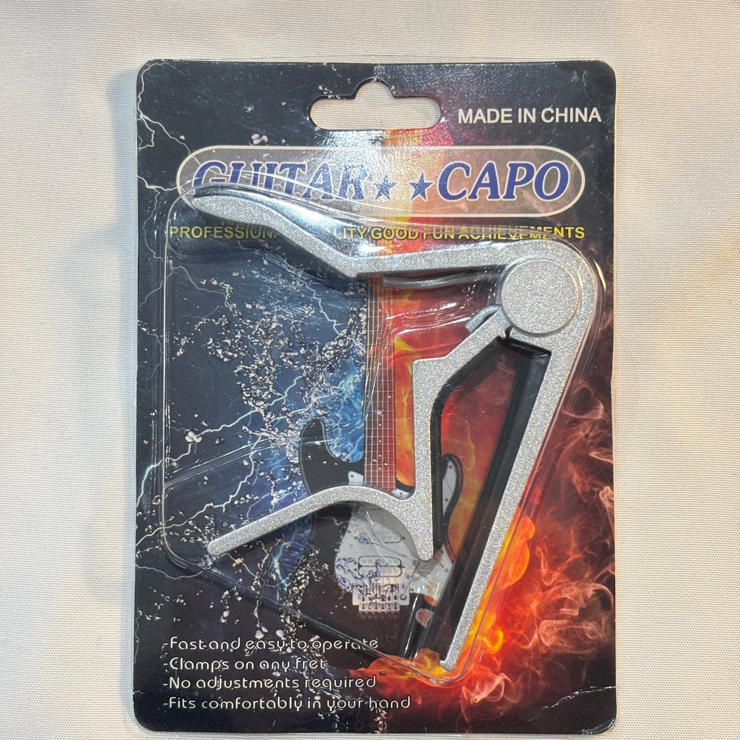 Guitar capo on a black card with colorful design on a white background.