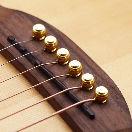 Close-up of six Acoustic Guitar Brass Bridge Pins photographed from above set in a Rosewood Bridge.
