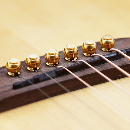 Close-up of an Acoustic Guitar's Brass Bridge Pins installed a Rosewood Bridge on an Acoustic Guitar.
