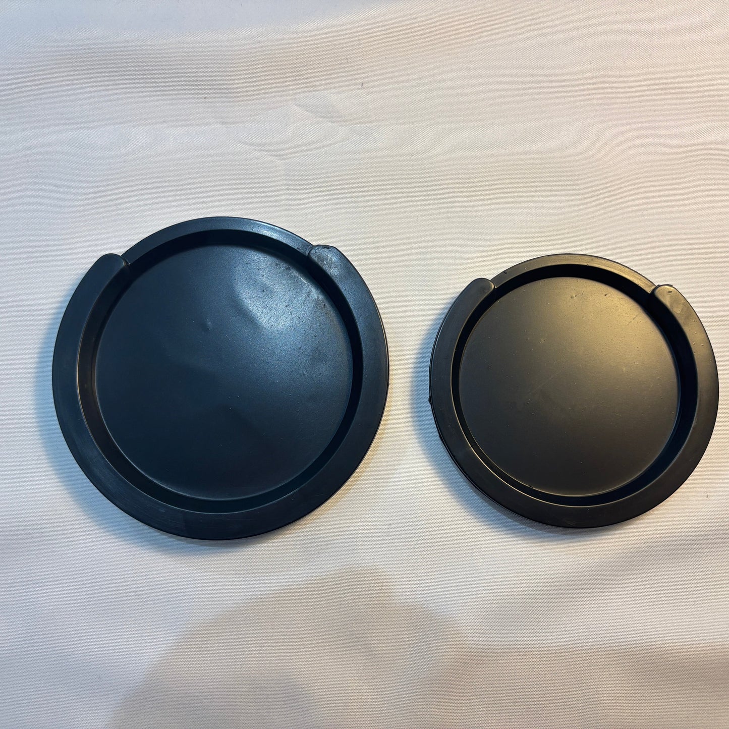 Two acoustic guitar Feedback Busters /Suppressors  on a light grey surface.