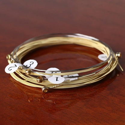 Acoustic Guitar Strings with number labels on a wooden surface.