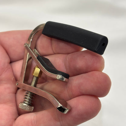 Alice acoustic / electric guitar capo in a hand against a white background.