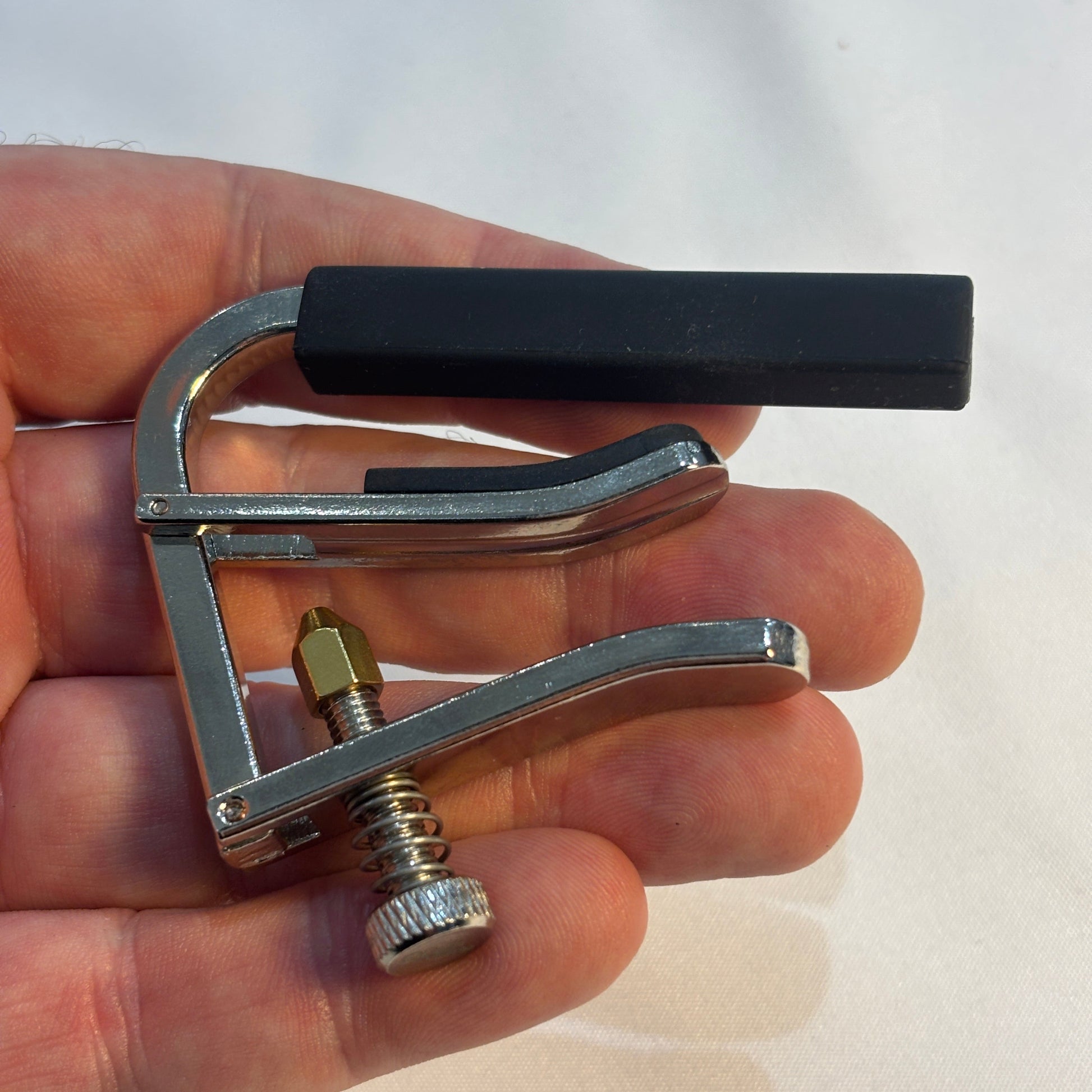 Alice classical guitar capo in a hand on a white background.