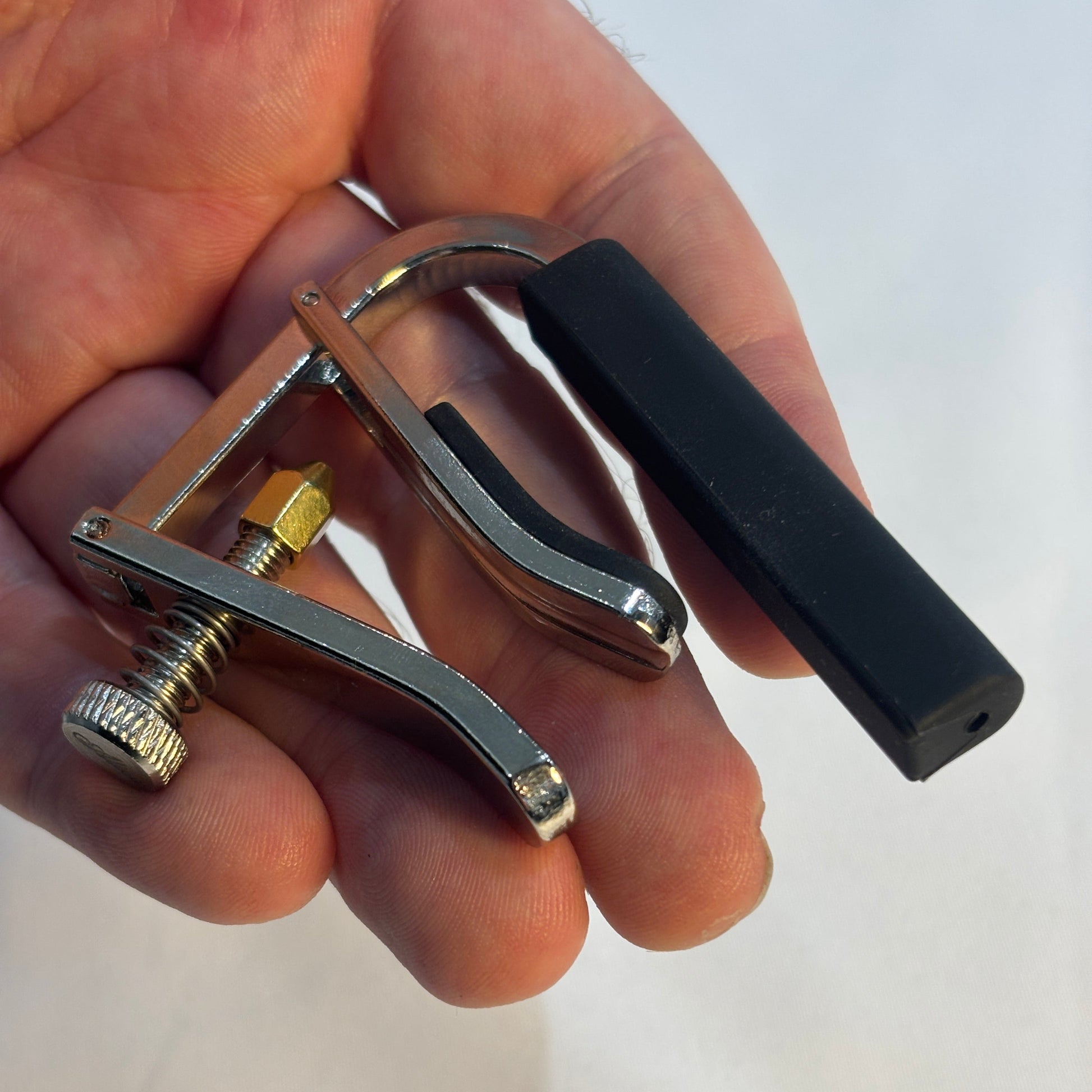 Alice classical guitar capo in a hand on a white background.