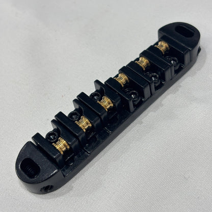 Black electric guitar roller bridge on a white background.