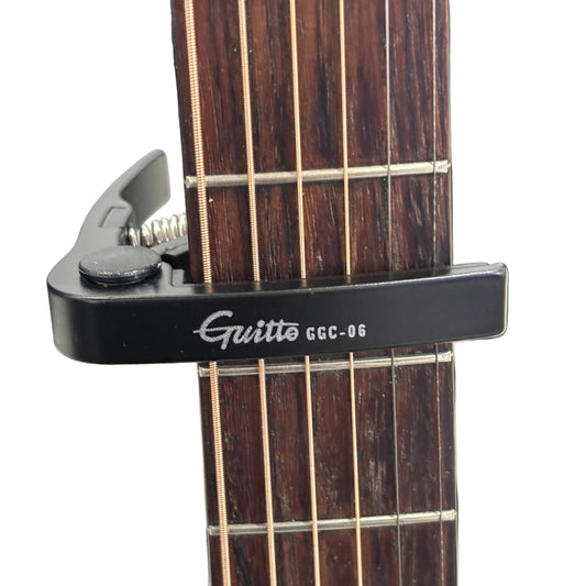 Guitar capo on an acoustic guitar against a white background