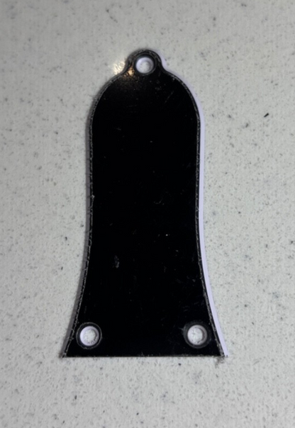 A black electric guitar Guitar Truss Rod Cover on a grey background.