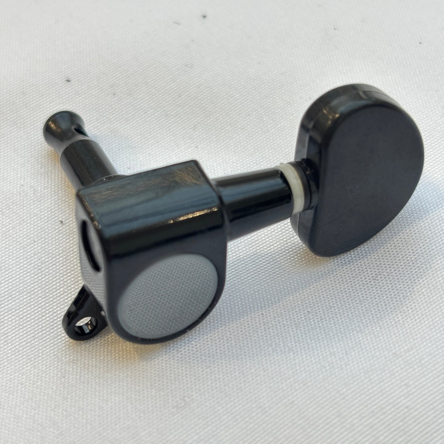 Black guitar tuner / machine head with kidney shaped button on a white background