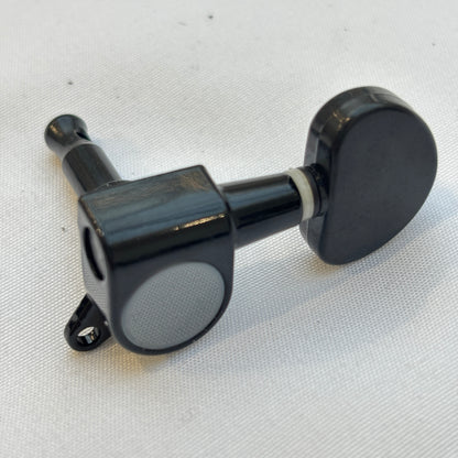 Black guitar tuner / machine head with kidney shaped button on a white background