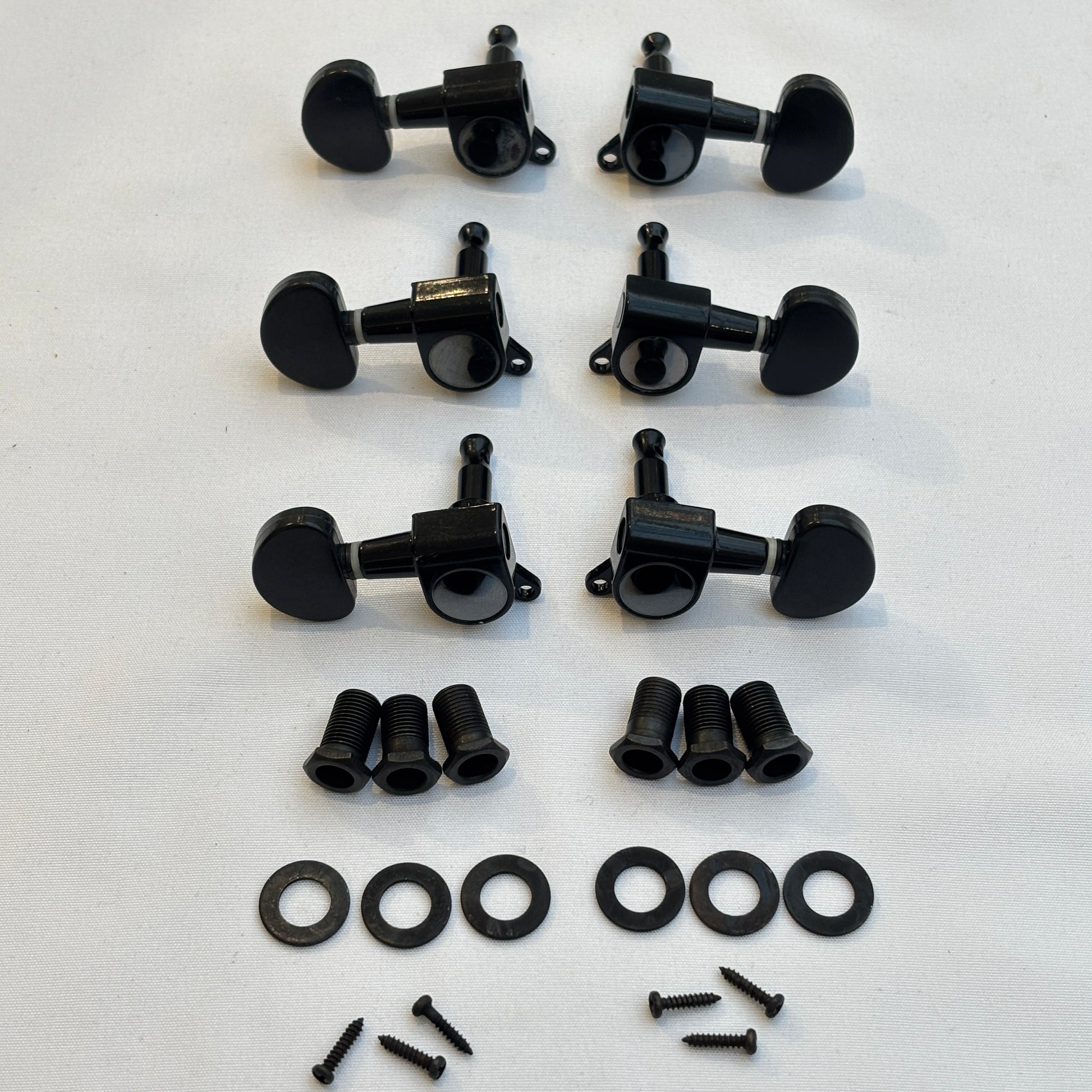 Set of black guitar tuners / machine heads with kidney shaped buttons and related parts on a white background