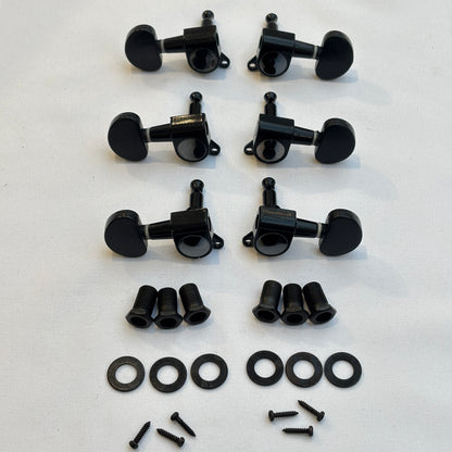 Set of black guitar tuners / machine heads with kidney shaped buttons and related parts on a white background