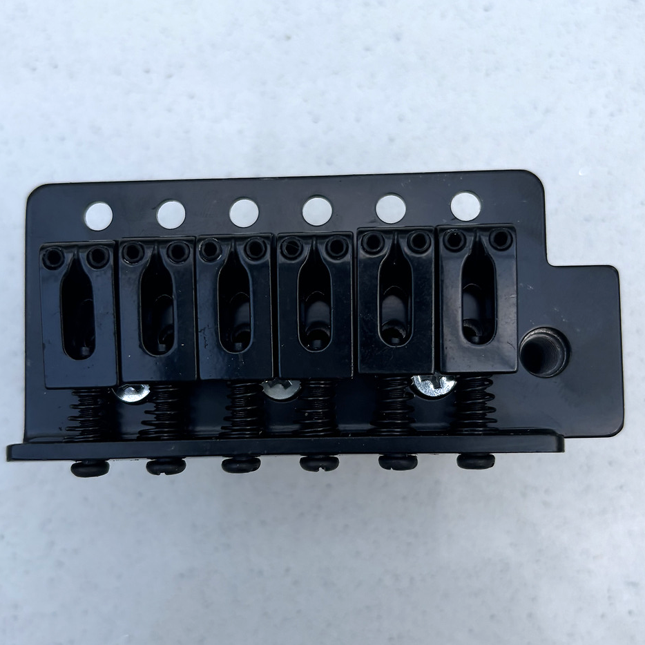 Gold Tremolo Bridge block on a grey background.