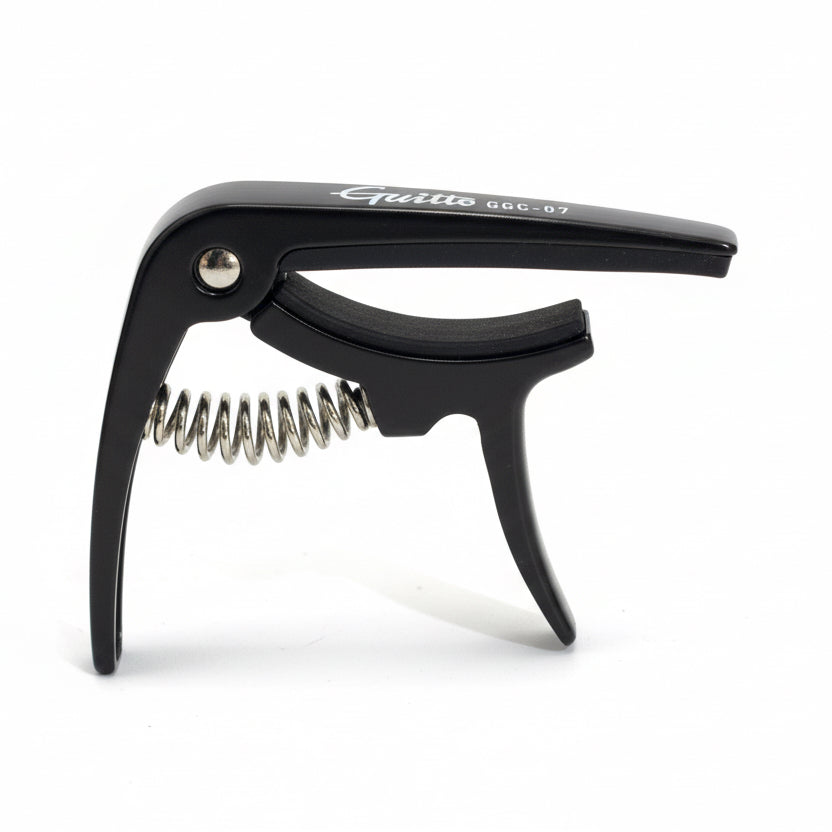 Black Ukulele capo held in a hand against a white background