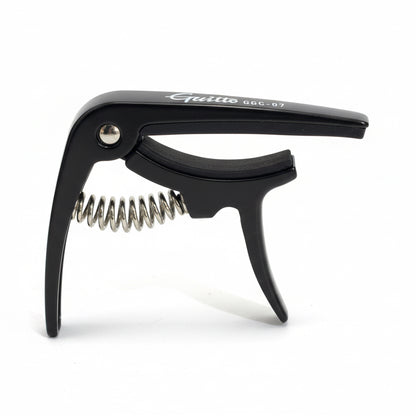 Black Ukulele capo held in a hand against a white background