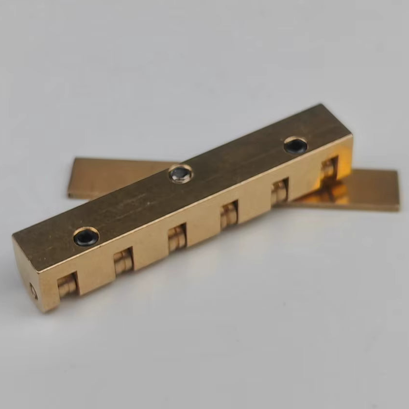 The underside of a brass electric guitar roller nut on a white background.