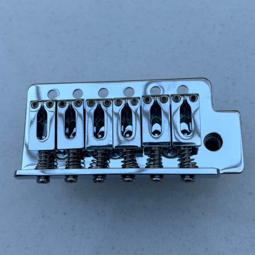Chrome Tremolo Bridge block on a grey background.