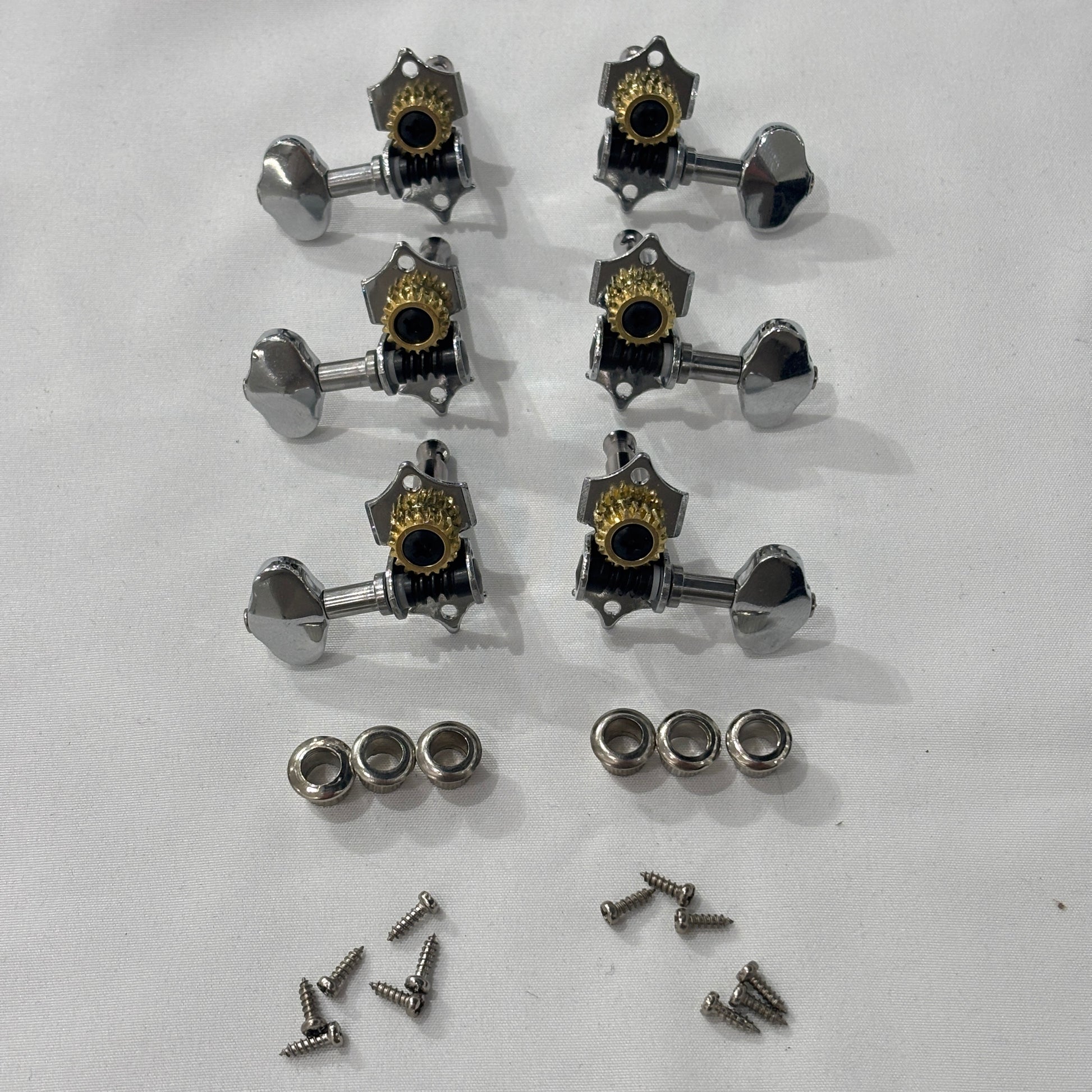 Set of chrome open back vintage acoustic guitar machine heads and fixings on a white background