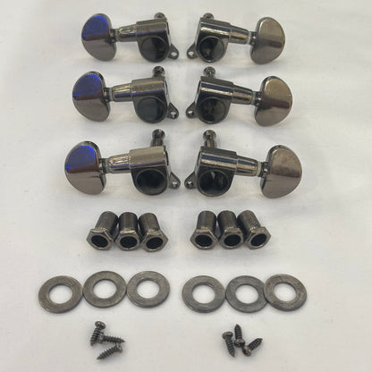 Set of dark nickel guitar tuners with kidney shaped buttons and related parts on a white background