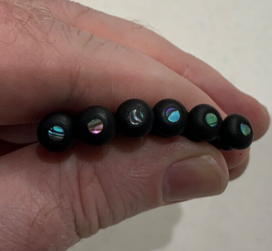Set of six Acoustic Guitar Bridge Pins with Abalone dots photographed in a hand.