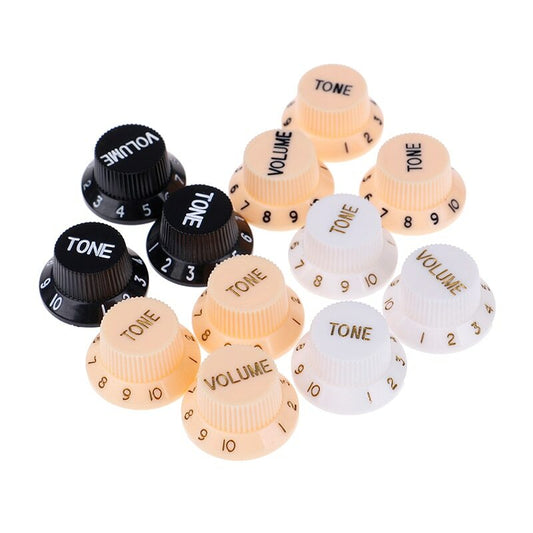 A mix of White, Cream and Black ST-style electric guitar Control Knobs on a white background.