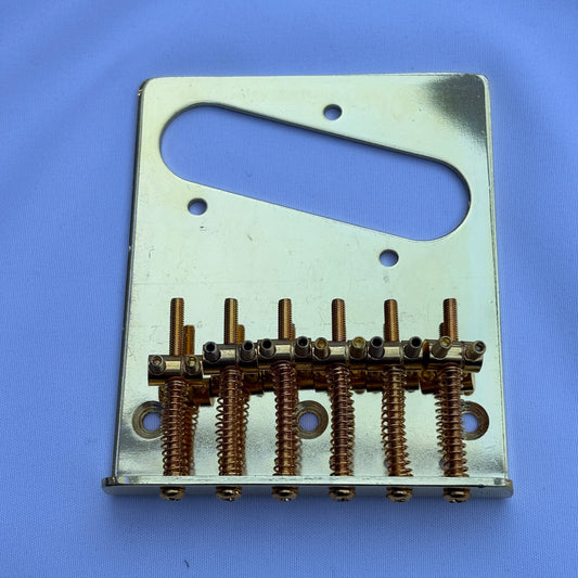 A gold modern electric guitar bridge, TL-style on a white background.