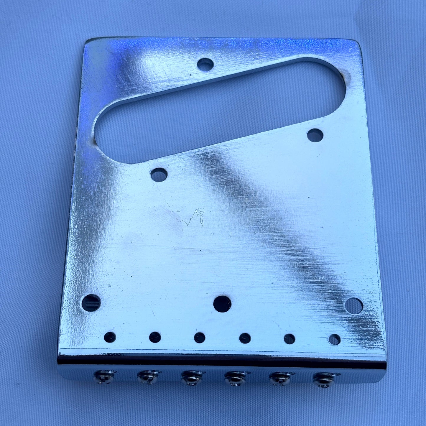 The back of a electric guitar modern guitar bridge in Chrome on a white background.