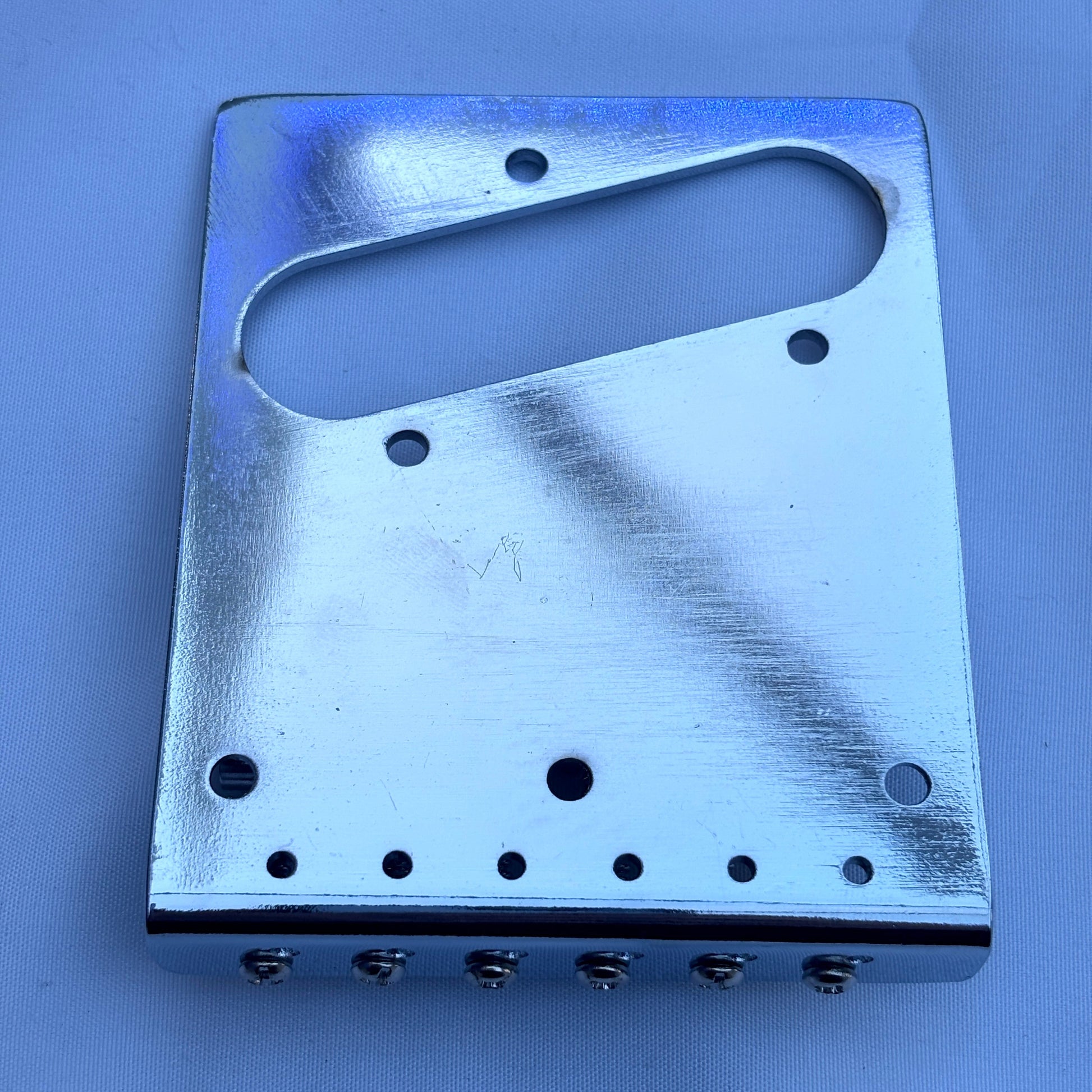 The back of a electric guitar modern guitar bridge in Chrome on a white background.