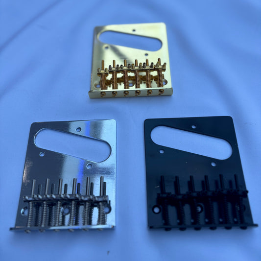 Three electric guitar modern guitar bridges in Gold, Chrome and Black, TL-style, on a white background.