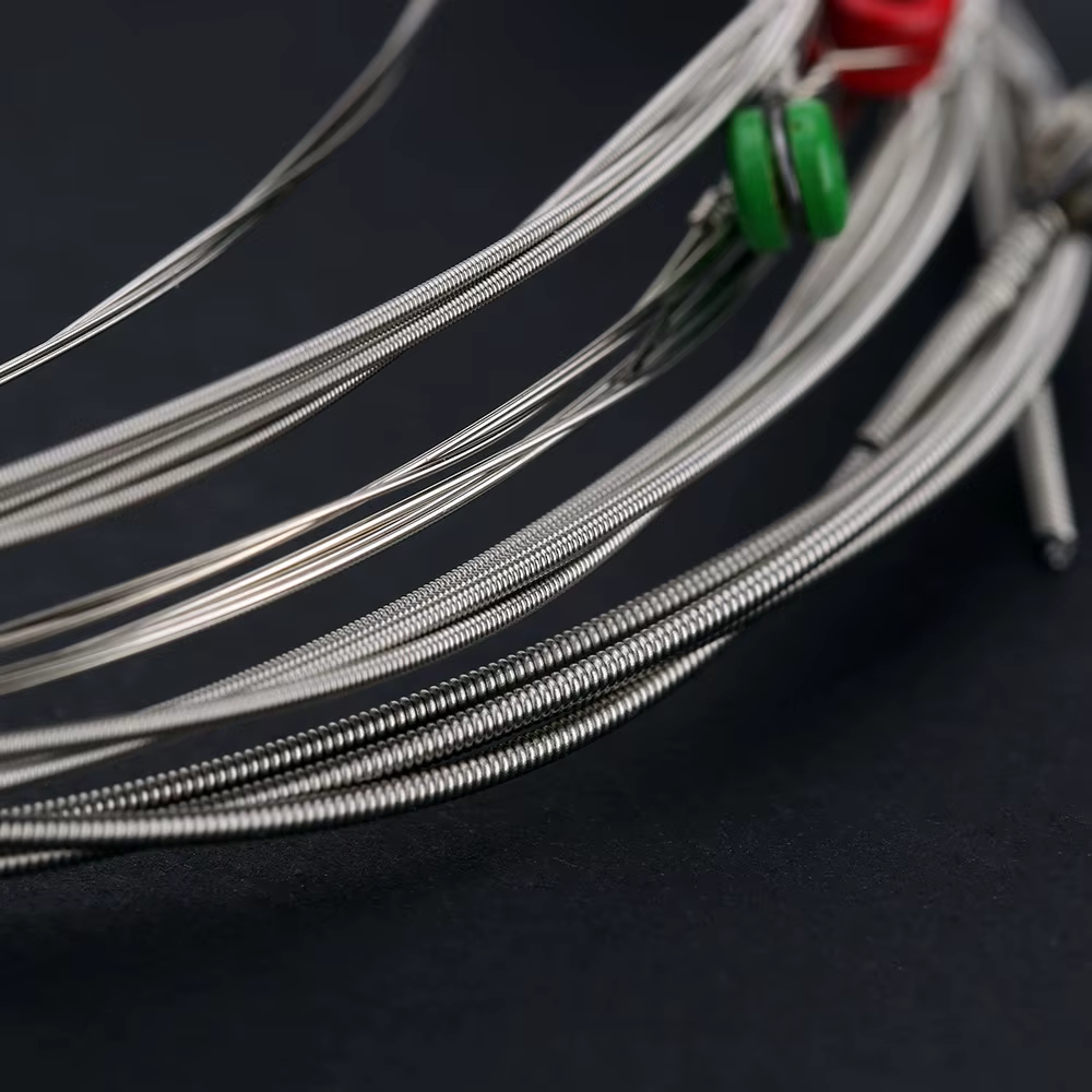 Set of close up of Electric Guitar strings with coloured ball ends on a dark background.