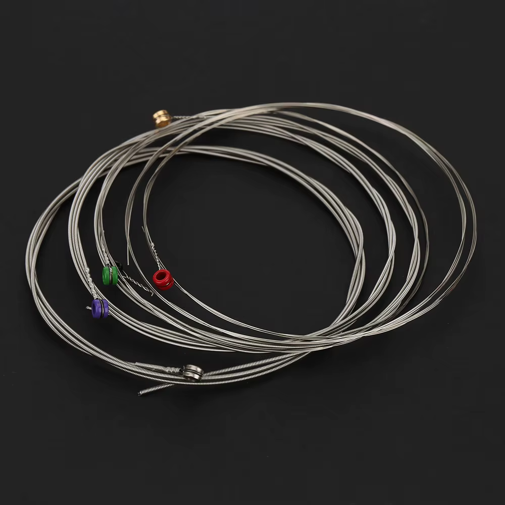 Set of Electric Guitar strings with coloured ends on a black background.