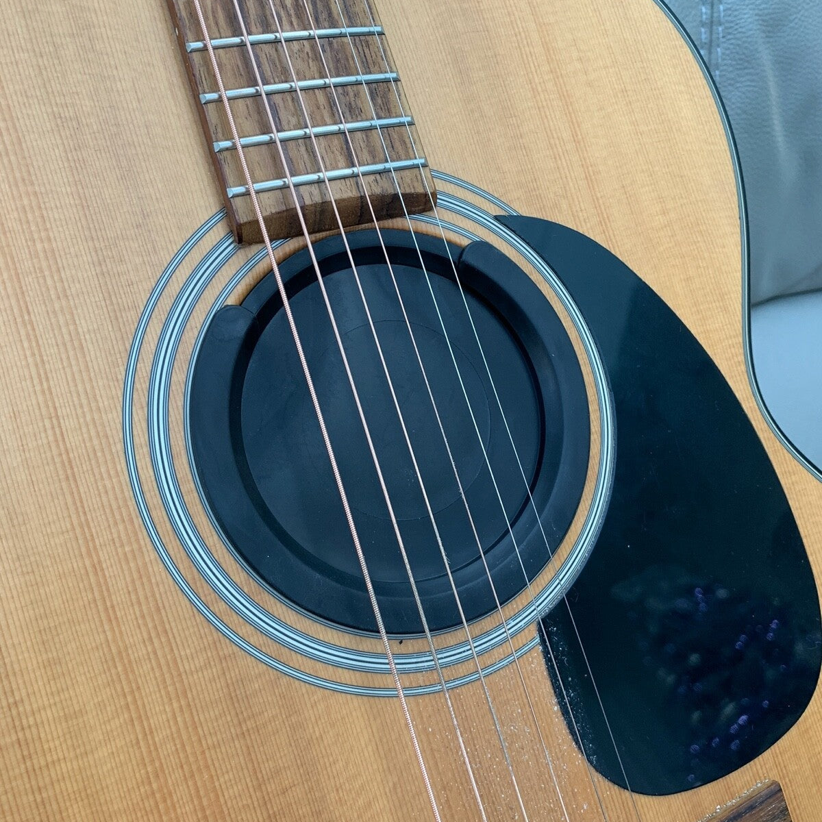 A Feedback Buster / Suppressor fitted to a budget acoustic guitar in a lounge.