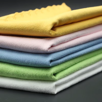 Stack of folded colourful Guitar Cleaning Cloths photographed from the side on a dark surface.