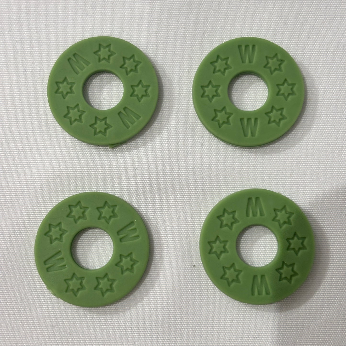 Four Green Rubber Guitar Strap Locks on a light grey background.