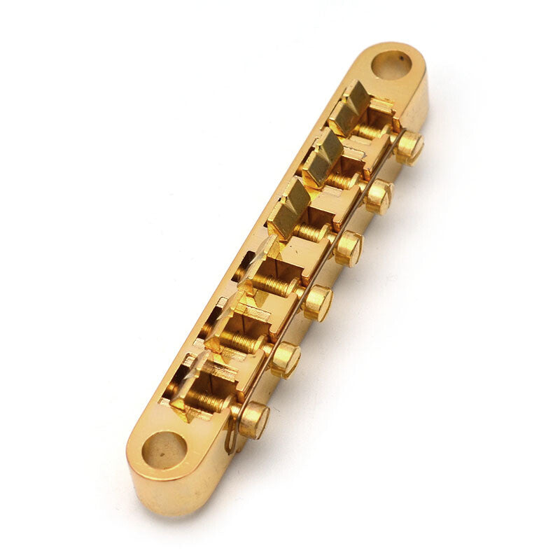 Electric guitar bridge in gold colour on a white background.