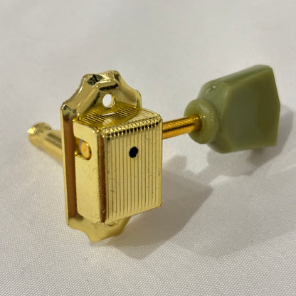 Gold Keystone guitar tuner / machine head with green buttons on a white background