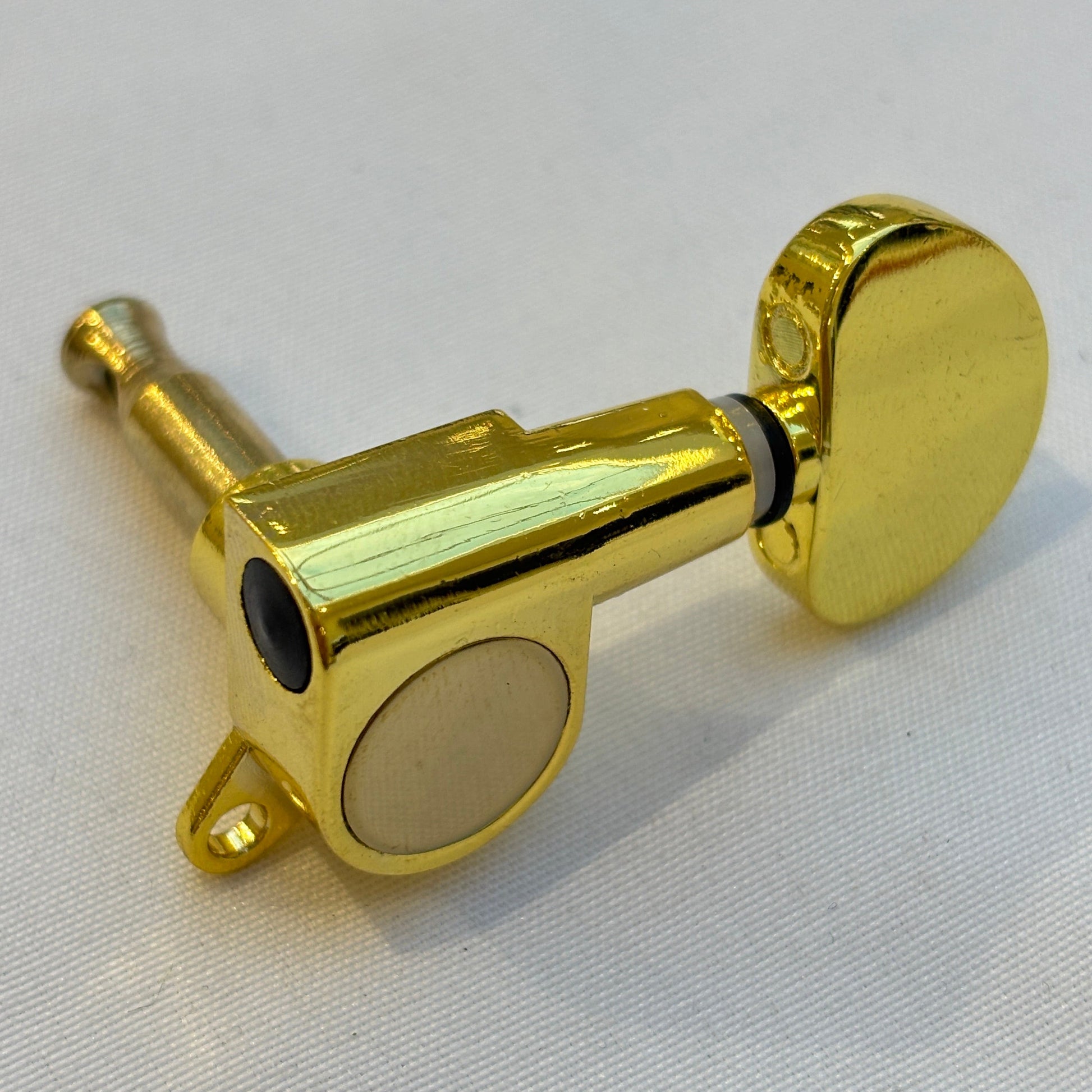 Gold guitar tuner / machine head with kidney shaped buttonon a white background