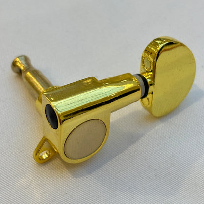 Gold guitar tuner / machine head with kidney shaped buttonon a white background