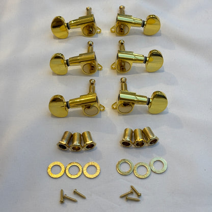 Set of gold guitar tuners with kidney shaped buttons and related parts on a white background