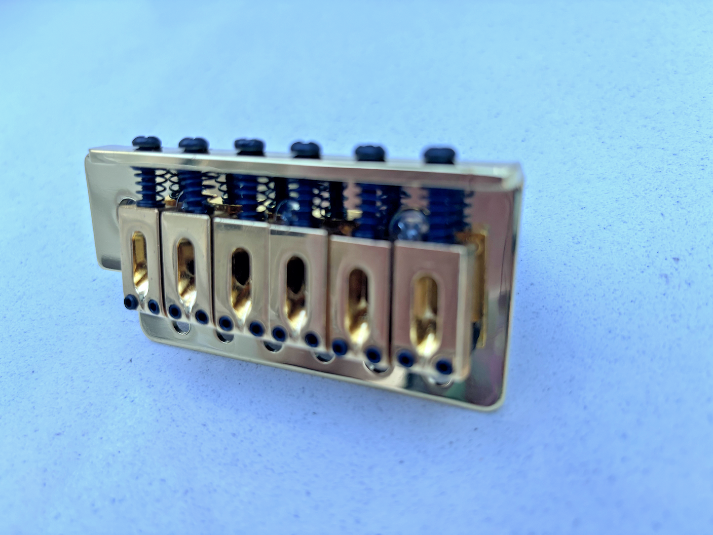 Gold Tremolo Bridge block on a grey background.