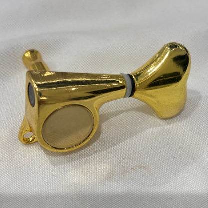 Gold Fish Tail Button Guitar Tuner on  textured fabric background.
