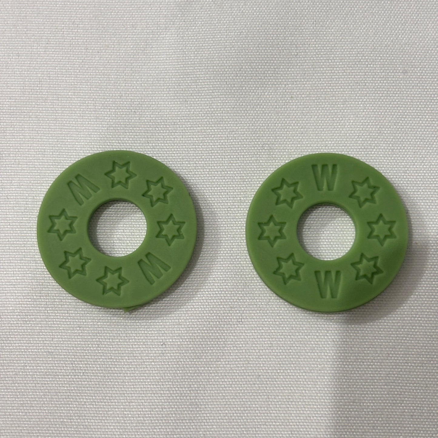 Two Green Rubber Guitar Strap Locks on a light grey background.