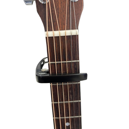 Guitar capo on a guitar neck with a white background.