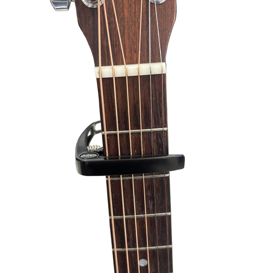 Guitar capo on a guitar neck with a white background.