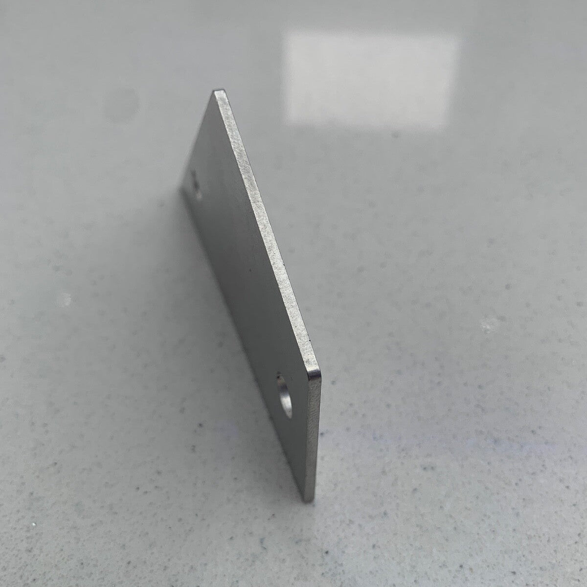 Guitar Fret Rocker photographed standing on its edge on a grey surface.